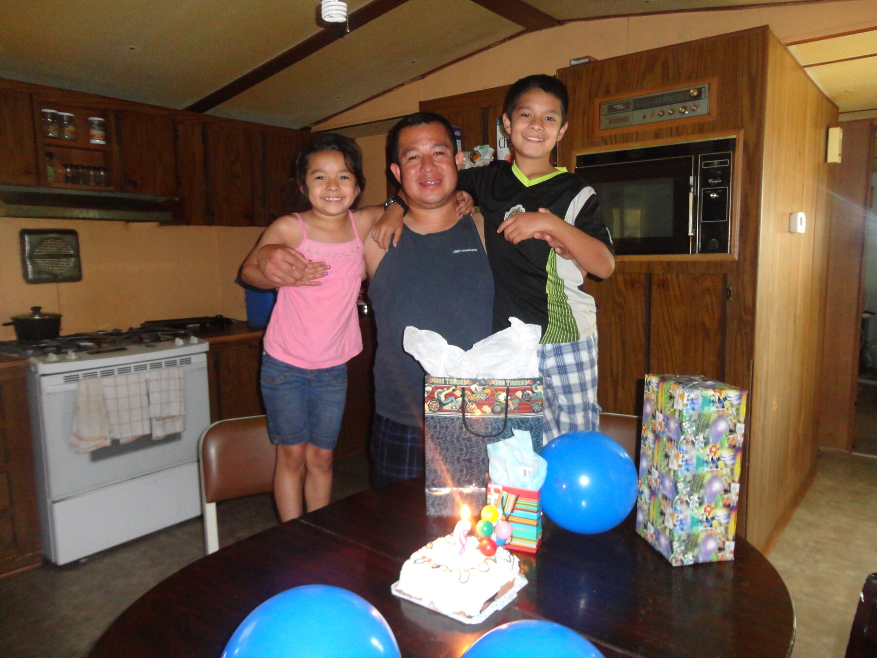 Homero standing with two children near a birthday table