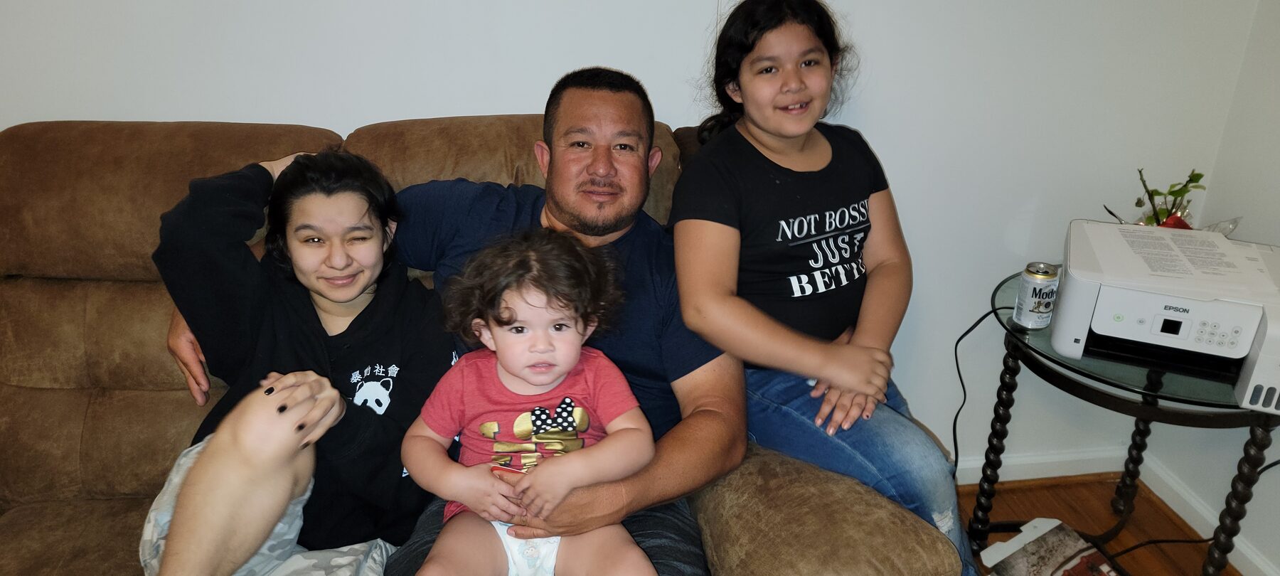 Homero seated on a couch surrounded by children