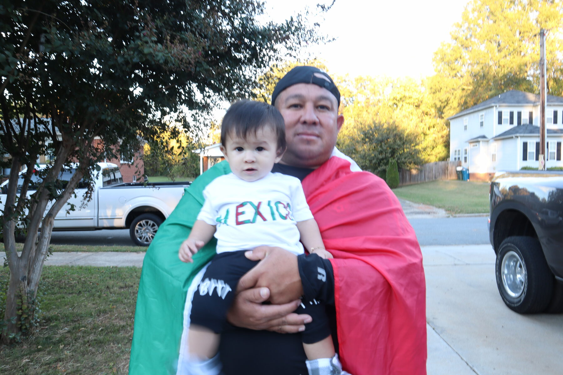 Homero holding a baby wrapped in green white and red