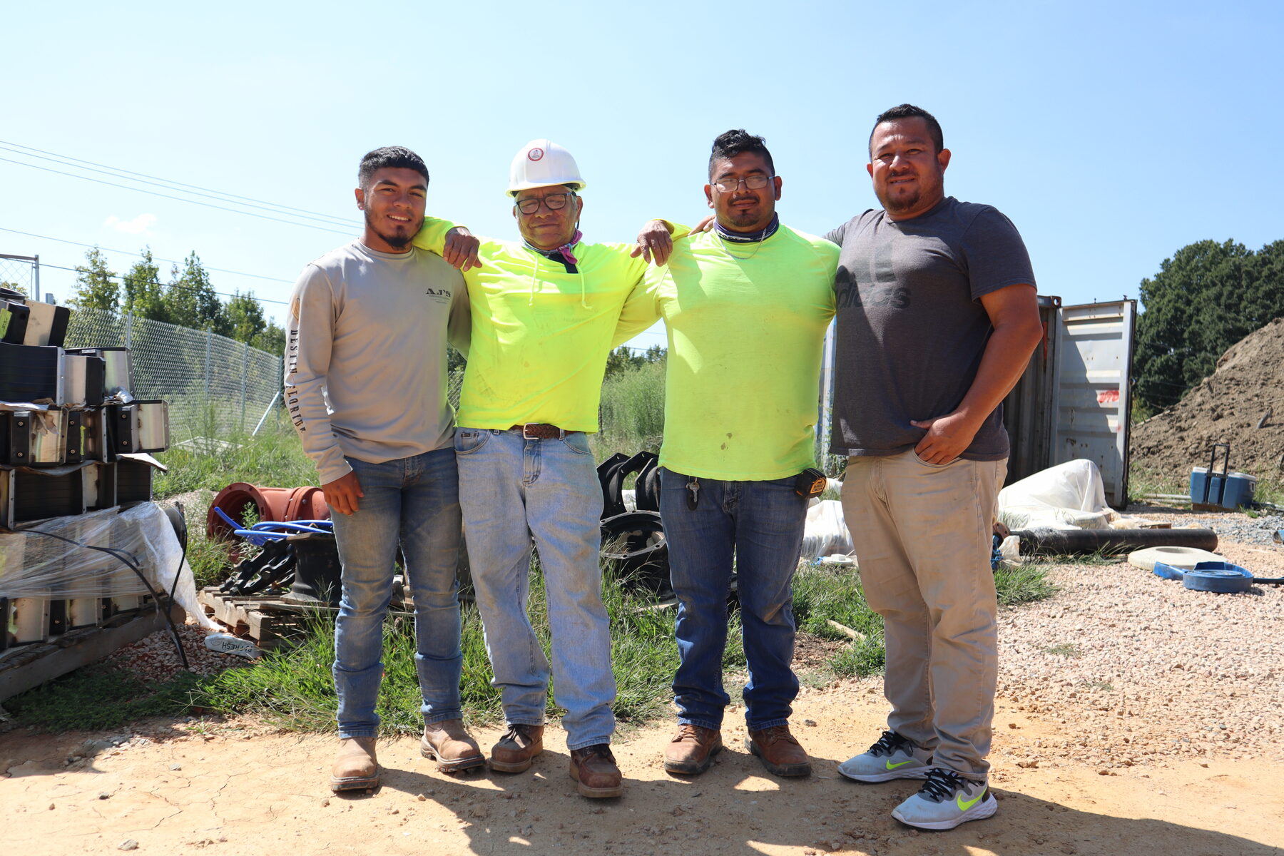 Homero standing with a construction crew beside heavy equipment