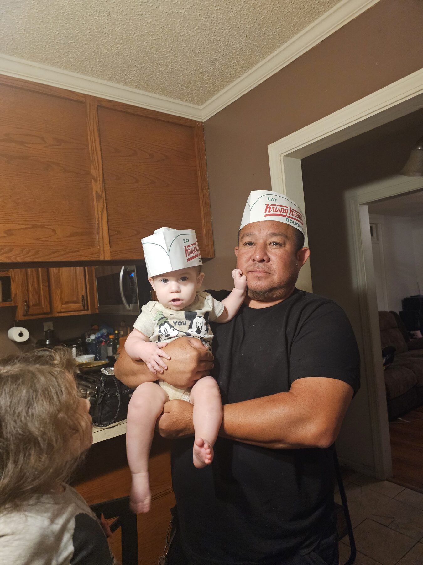 Homero holding a baby in the kitchen